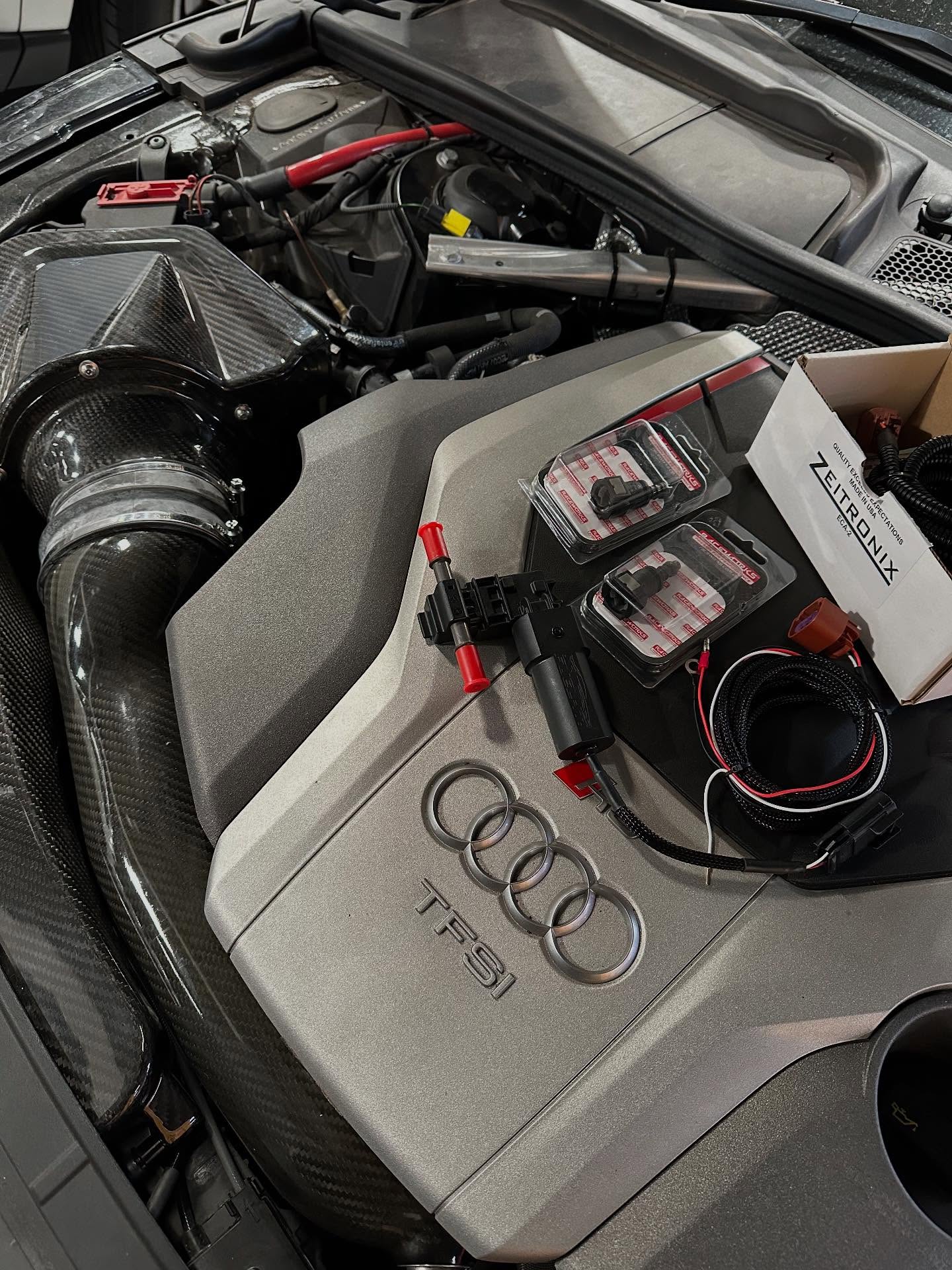 Carbon fibre intake and engine cover in an open engine bay with parts laid out