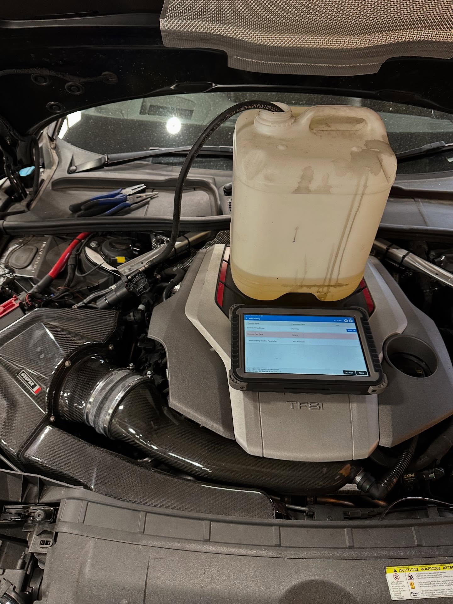 Diagnostic tablet resting on an engine cover during a vehicle check