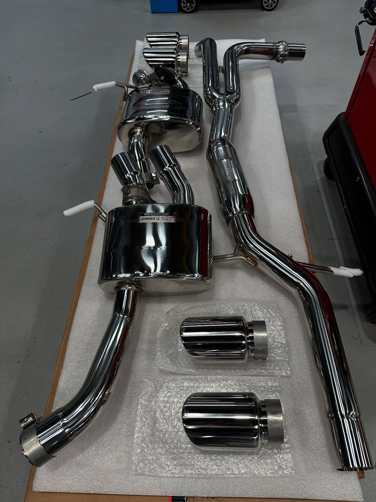 Polished stainless steel exhaust sections and tips laid out on a table
